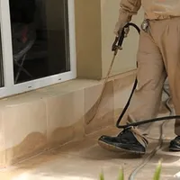 General pest control technician spraying exterior perimeter around a home in Oklahoma City, OK