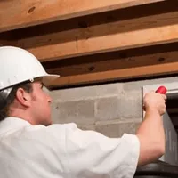 Termite inspection technician checking a basement wall and framing for termite activity in Oklahoma City, OK