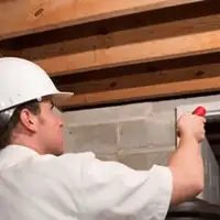 Termite inspection technician checking a basement wall and framing for termite activity in Oklahoma City, OK